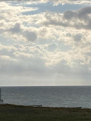 Ein Blick auf die Ostsee und einen weiten, wolkigen Himmel mit Sonnendurchbrüchen