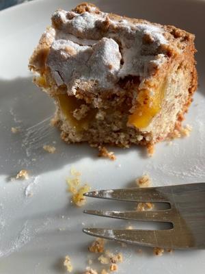 Ein angebissenes Stück Lemoncurd Linzertorte auf einem Teller mit Krümeln und einer Gabel daneben