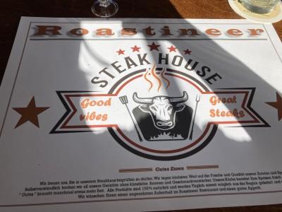 Ein weißes Papierdeckchen mit dem Schrifzug des Restaurants Roastinner