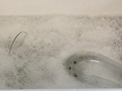 Ein mit Schaum bedecktes Spülbecken in der Mitte ein liegendes Glas